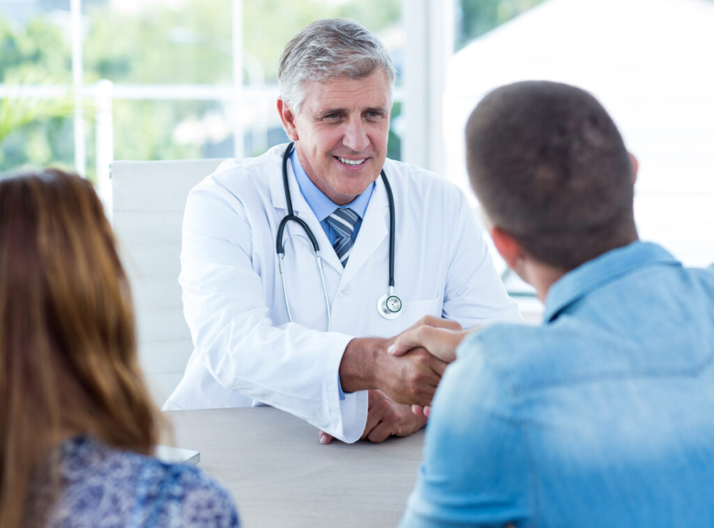 smiling-doctor-greeting-happy-couple 1 smiling-doctor-greeting-happy-couple